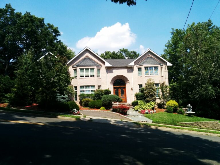 Large suburban colonial home with mature foundation plantings, curved beds and a green front lawn